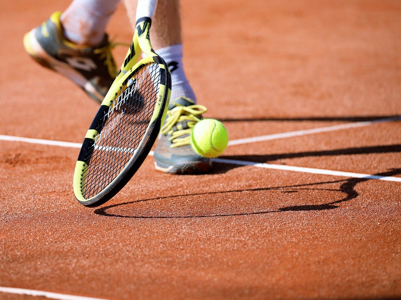 tennis racket swinging to hit tennis ball